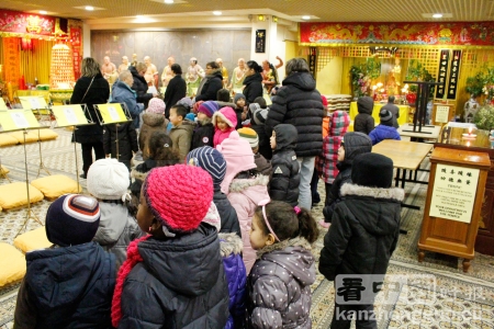 黎先生带着孩子们和老师及家长在法国潮州会馆佛堂中参观(摄影：溪客)