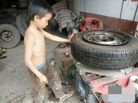 小男孩仅仅10岁，正在熟练地修理汽车，更换轮胎。（网络图片）
