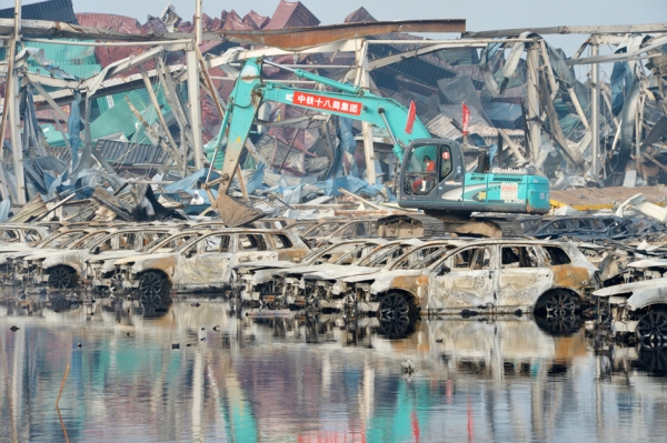 天津大爆炸后，救援人员操作大型机械正在清理损坏的汽车。(AFP/Getty Images)