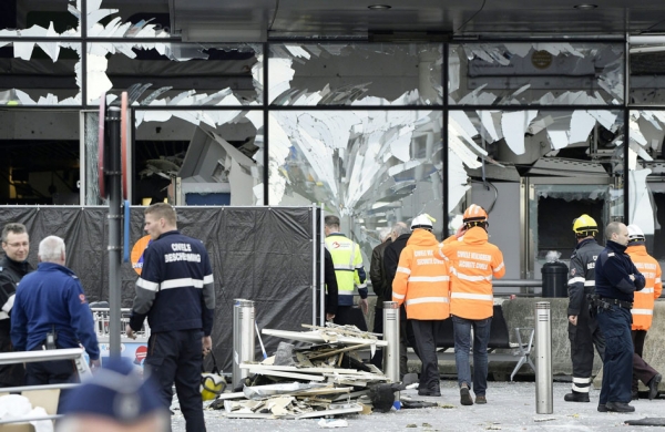 3月22日，在布鲁塞尔机场爆炸发生后的第二天，工作人员在受损的机场大厅前。（AFP/Getty Images）