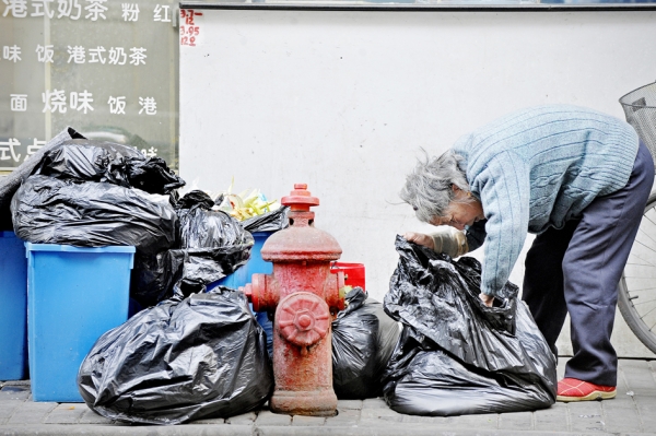 在上海一家餐馆外，一名老年妇女在垃圾带中寻找食物。（Getty Images）