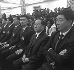 傅政华(右)被拍到在李克强记者会上现身，面无表情坐在现场，身边有四个坐姿标准的黑衣人。(网络图片)