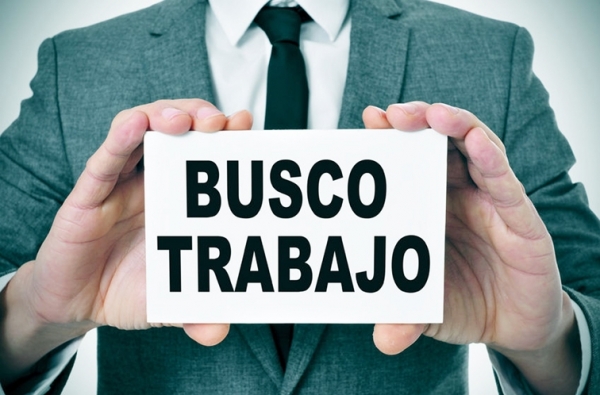 一名男子穿着西装拿着西班牙语“BUSCO TRABAJO(找工作)”招牌在找工作。（123RF）