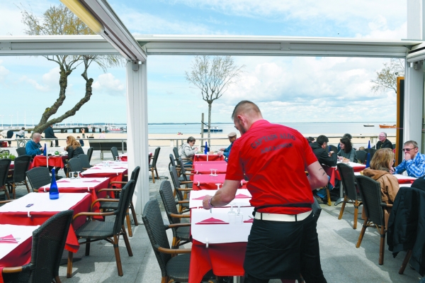 一名服务员在法国西南部海滨度假小镇的一家餐厅为客人准备餐点。（MEHDI FEDOUACH/AFP/Getty Images）