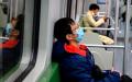 2020年2月14日，一名戴着防护口罩的青年在火车上睡觉。（图片来源：NOEL CELIS/AFP via Getty Images）