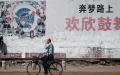 2018年5月29日，辽宁丹东的一位路人骑自行车经过一副中国梦的标语牌。（图片来源：FRED DUFOUR/AFP via Getty Images）