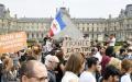 2021年7月17日，在巴黎卢浮宫外，抗议者手持写有“反对健康通行证”的标语牌，反对法国政府要求的强制健康安全措施。（BERTRAND GUAY/AFP via Getty Images）