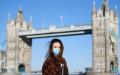 一名戴口罩的女士在英国伦敦塔桥前合影留念。（Alex Davidson/Getty Images）