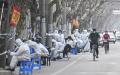 2022年3月14日，身穿防护服的人员在上海一处因疫情封锁的地区工作。（HECTOR RETAMAL/AFP via Getty Images）