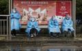 2022年11月11日，几位穿防护服的工作人员在北京一处购物节广告牌前。（Kevin Frayer/Getty Images）
