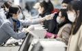 图为机场一名工作人员正在测量旅客体温。（Tomohiro Ohsumi/Getty Images）