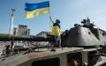 图为2022年8月21日，在乌克兰首都基辅市中心，一个小男孩手持并身裹一面乌克兰国旗站在一辆被缴获的俄罗斯军车上。（Alexey Furman/Getty Images）