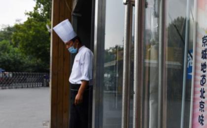 中国大陆餐饮业竞争日趋激烈，2024年第一季度有近46万家餐饮企业关闭。图为2020年9月14日，北京一名厨师站在一家餐厅的入口处等待顾客到来。 （图片来源：GREG BAKER/AFP via Getty Images）