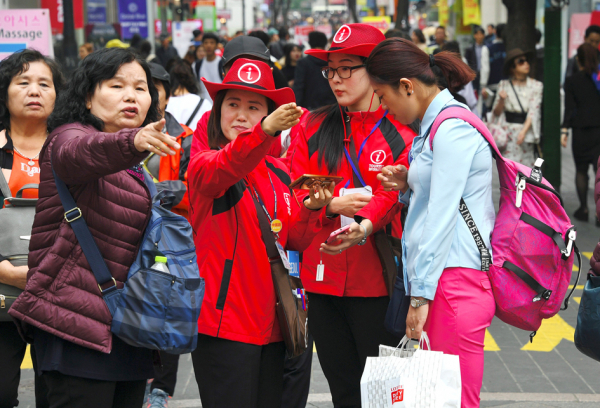 韩国旅游信息助手（红色）在首尔著名的明洞购物区引导大陆游客。（Getty Images）