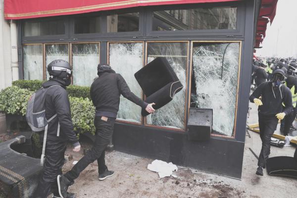 黄背心第18次行动中在香榭丽舍大街上砸毁标志性奢侈餐厅Le Fouquet's的黑衣蒙面人。（AFP/Getty Images）