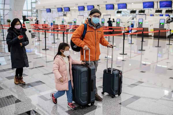 图为1月22日，戴着口罩的一家三口在北京机场。（AFP via Getty Images）