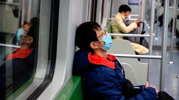 2020年2月14日，一名戴着防护口罩的青年在火车上睡觉。（图片来源：NOEL CELIS/AFP via Getty Images）