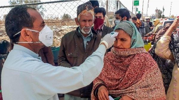 2020年2月29日，一名工作人员检查从伊朗经巴基斯坦与伊朗边境小镇塔夫坦（Taftan）返回伊朗的朝圣者的体温。(图片来源:STR/AFP via Getty Images)