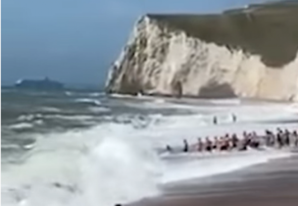 日前，英国杜德尔门逾30人牵一线，拉回巨浪冲走泳客。（图片来源：视频截图)