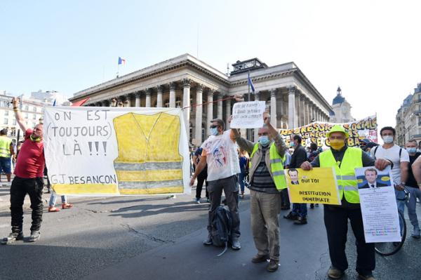 2020年9月12日，在巴黎举行的黄背心（Gilets jaunes）运动号召的示威活动中，戴着保护面罩的抗议者手持标语牌和横幅。（AFP/Getty Images）