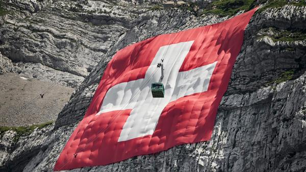 挂在山岩上的巨幅瑞士国旗（FABRICE COFFRINI/AFP via Getty Images）