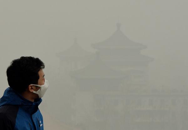 2014年2月26日，北京雾霾严重，一名戴着口罩的游客爬上紫禁城旁的景山。（MARK RALSTON/AFP via Getty Images）