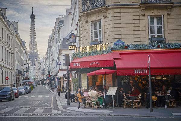 2021年5月19日，巴黎市区一家餐馆迎来在露台就餐的顾客，街道尽头的背景是埃菲尔铁塔。（Kiran Ridley/Getty Images）