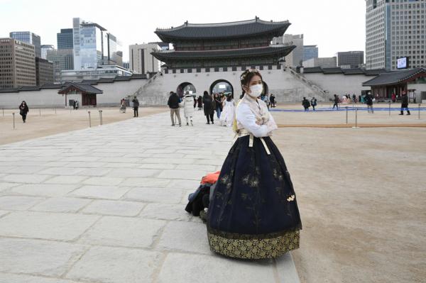 一名身穿韩国传统韩服的女子站立在首尔景福宫前。（JUNG YEON-JE/AFP via Getty Images）
