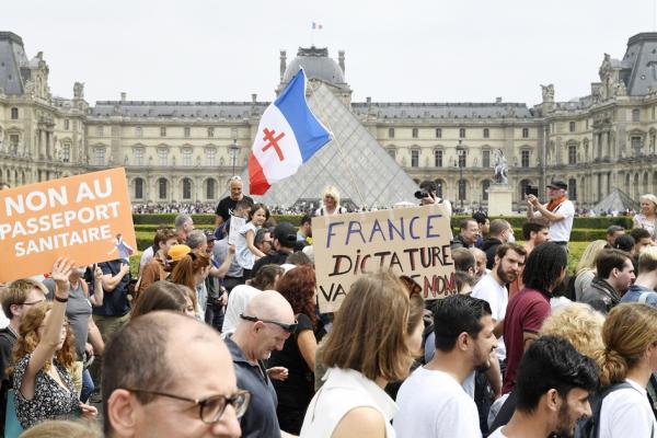 2021年7月17日，在巴黎卢浮宫外，抗议者手持写有“反对健康通行证”的标语牌，反对法国政府要求的强制健康安全措施。（BERTRAND GUAY/AFP via Getty Images）