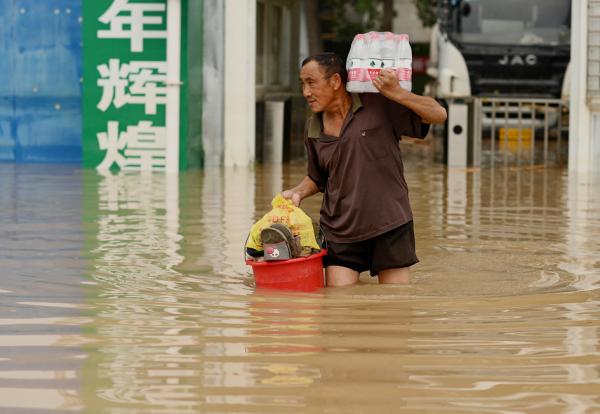 7月23日，郑州市一名男子穿过被洪水淹没的街道。（NOEL CELIS/AFP via Getty Images）