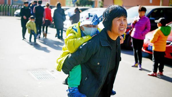 一位中国妇女背着一个孩子。（WANG ZHAO/AFP via Getty Images）