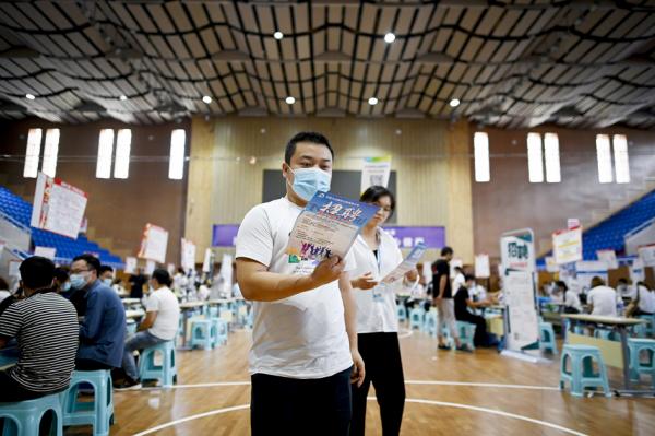2020年7月25日，一名求职者在河南郑州举行的招聘会上查看信息传单（WANG ZHAO/AFP via Getty Images）