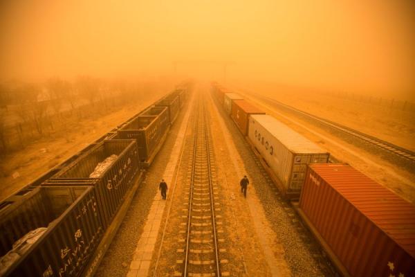 图为2023年3月21日内蒙古地区的边境城市二连浩特，警察在沙尘暴中检查火车车厢。 （图片来源：STR/AFP via Getty Images)