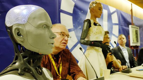 欧盟在12月8日达成里程碑意义的AI监管法规。图为：2023年7月7日在瑞士日内瓦举行的新闻发布会上，英国制造商Engineered Arts首席执行官兼创始人Will Jackson旁边的人形机器人Ameca（左）向媒体发表讲话。（Johannes Simon/Getty Images）