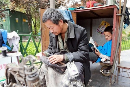 航航正蜷缩在修鞋车里读书。(网络图片) 航航正蜷缩在修鞋车里读书。(网络图片)