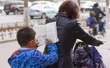 早晨,一位看上去只有一二年级的小学生趴在妈妈后背上看书学习。 早晨,一位看上去只有一二年级的小学生趴在妈妈后背上看书学习。