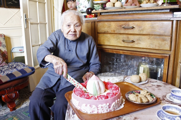 萍姑正在切王可阳先生特别为她制作的寿桃蛋糕。（摄影：林莲怡/看中国）