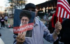 在2月28日于美国乔治亚州亚特兰大举行的集会上，一名男子手持美国国旗和写着哈梅内伊“已被清除”的标牌。（图片来源：Getty Images）