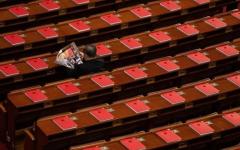 2026年3月12日，在全中共国人民代表大会闭幕式前，一名代表正在北京人民大会堂里阅读关于会议的杂志，桌上可见红色书籍。（图片来源：Getty Images）