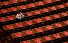 2026年3月12日，在全中共国人民代表大会闭幕式前，一名代表正在北京人民大会堂里阅读关于会议的杂志，桌上可见红色书籍。（图片来源：Getty Images）