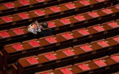 2026年3月12日，在全中共国人民代表大会闭幕式前，一名代表正在北京人民大会堂里阅读关于会议的杂志。（图片来源：Kevin Frayer/Getty Images）
