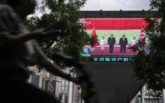 2026年6月8日，一名女子骑车经过北京一家购物中心外的大萤幕，萤幕上正在播放中共党魁习近平与北韩领导人金正恩在北韩会晤的新闻报道。(图片来源：Pedro PARDO/AFP via Getty Images)