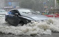 2026年7月7日，一辆汽车行驶在北京一条被洪水淹没的街道上。（图片来源：Adek BERRY / AFP via Getty Images）