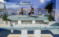 2012年11月12日，在珠海第九届中国国际航空航天博览会开幕前夕，几名男子坐在中国北方工业集团有限公司（中国兵器工业集团）的导弹模型展台旁。（图片来源：PHILIPPE LOPEZ/AFP via Getty Images）