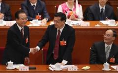 2013年3月5日，时任中共总理温家宝（左）在北京人民大会堂举行的中共全国人大会议开幕式上发表政府工作报告后，与时任中共副总理李克强（右）握手，时任中共副总理王岐山（右）在一旁注视。（图片来源：Feng Li/Getty Images）