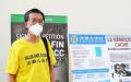 李旭彤博士摄于7月17日法轮功反迫害集会的展板前。