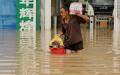7月23日，郑州市一名男子穿过被洪水淹没的街道。（NOEL CELIS/AFP via Getty Images）