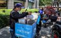  外卖人员在北京一条街道上检查食品订单，示意图。（图片来源：JADE GAO/AFP via Getty Images）