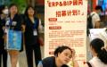 资料照片：2023年6月9日，一名招聘人员在北京一家购物中心招聘会的展位上与申请人交谈。（图片来源：网络截图）