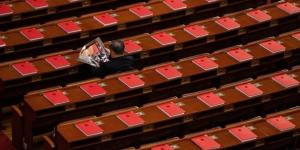 2026年3月12日，在全中共国人民代表大会闭幕式前，一名代表正在北京人民大会堂里阅读关于会议的杂志，桌上可见红色书籍。（图片来源：Getty Images）